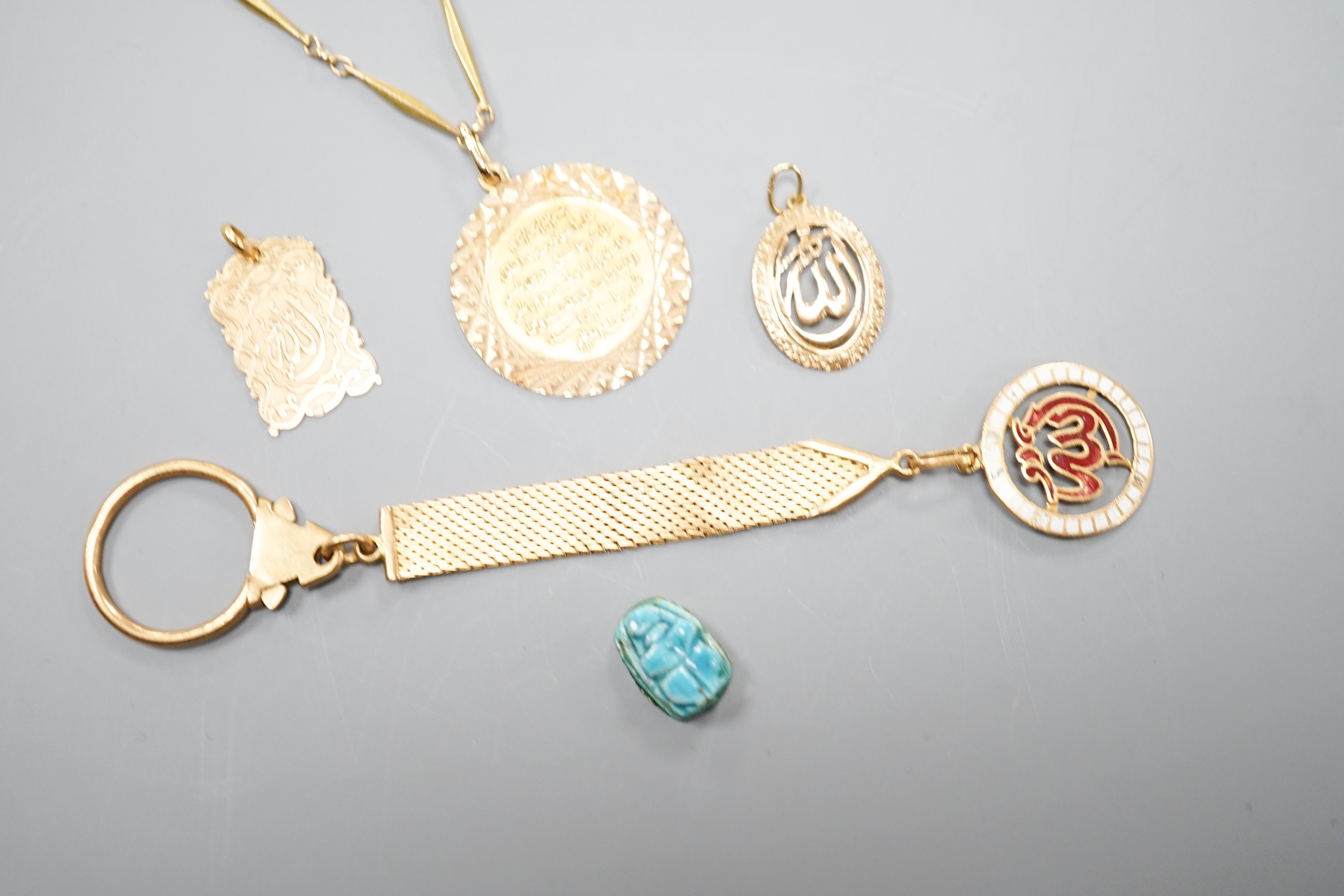 A Middle Eastern yellow metal and enamel pendant on a similar clip and three other Middle eastern pendants, one with chain, gross weight 34.5 grams and an Egyptian scarab.